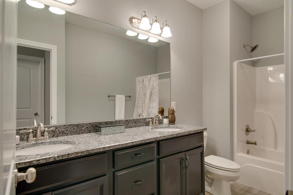417 Kaiser Road Dickson, TN 37055 - Photo 24 of 30 a bathroom with a granite countertop sink a toilet and a mirror