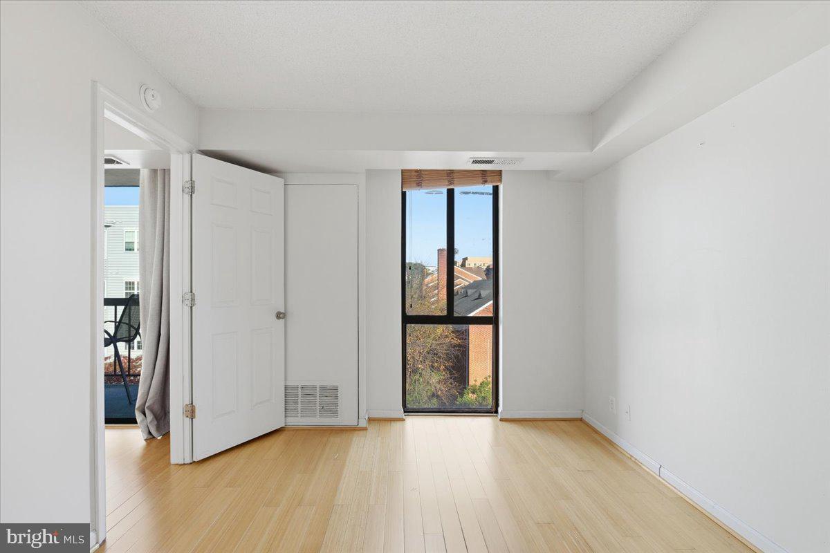 1401 North Rhodes Street, Unit 503 Arlington, VA 22209 - Photo 13 of 25 a view of an empty room with wooden floor and a window