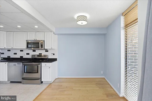 a kitchen with granite countertop white cabinets stainless steel appliances and sink
