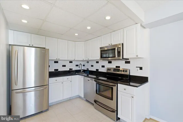a kitchen with a refrigerator sink and white cabinets