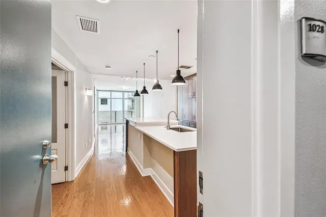 a view of an empty room with wooden floor and a ceiling fan
