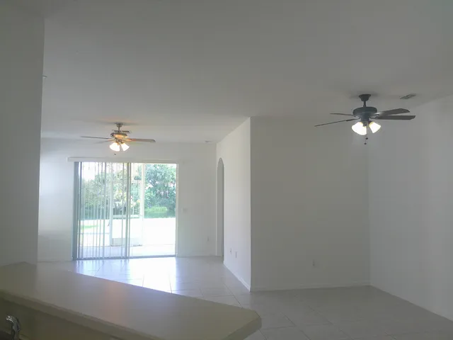 an empty room with windows and ceiling fan
