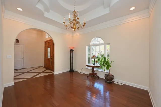 an empty room with wooden floor chandelier and windows