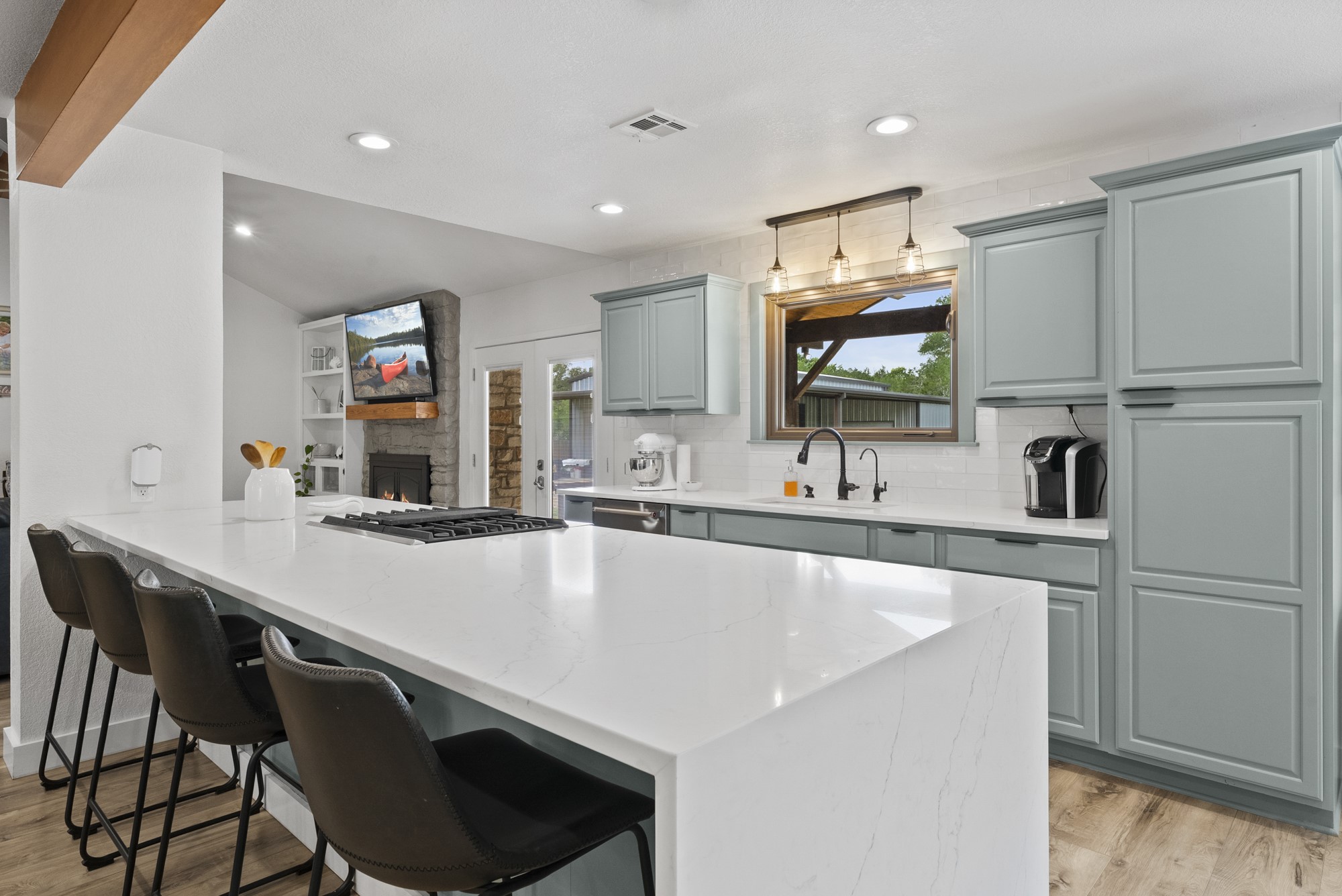 2802 Robin Road Manchaca, TX 78652 - Photo 7 of 40 Gourmet kitchen featuring a large island with cooktop, light-toned countertops, gray cabinetry, subway tile backsplash, and wood-finish flooring