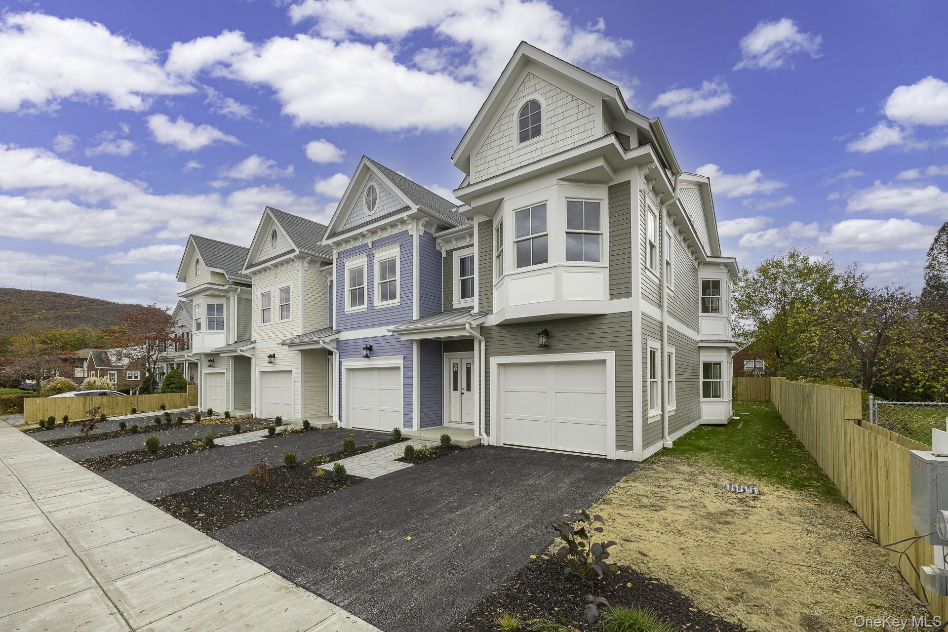 Victorian-style house with an attached garage, a residential view, and asphalt driveway