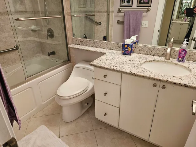 a bathroom with a granite countertop sink toilet and shower