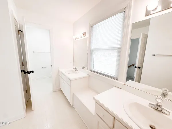 a bathroom with a double vanity sink a mirror and a bathtub