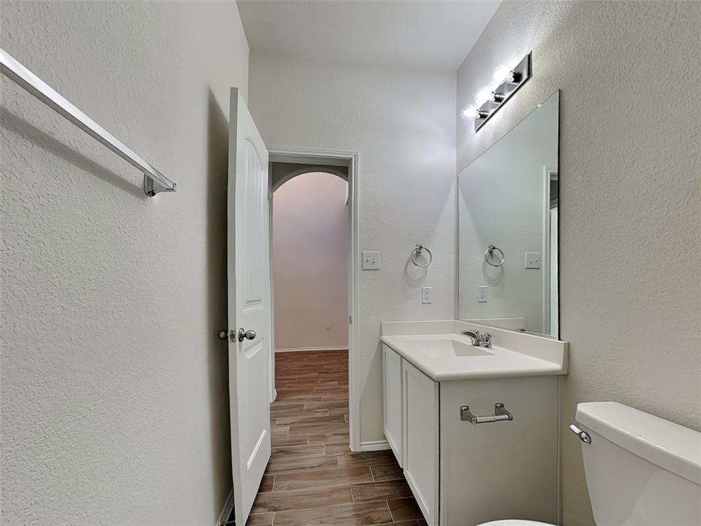 506 Robinson Way Fate, TX 75189 - Photo 22 of 30 Half bath with a textured wall, vanity, and wood finish floors
