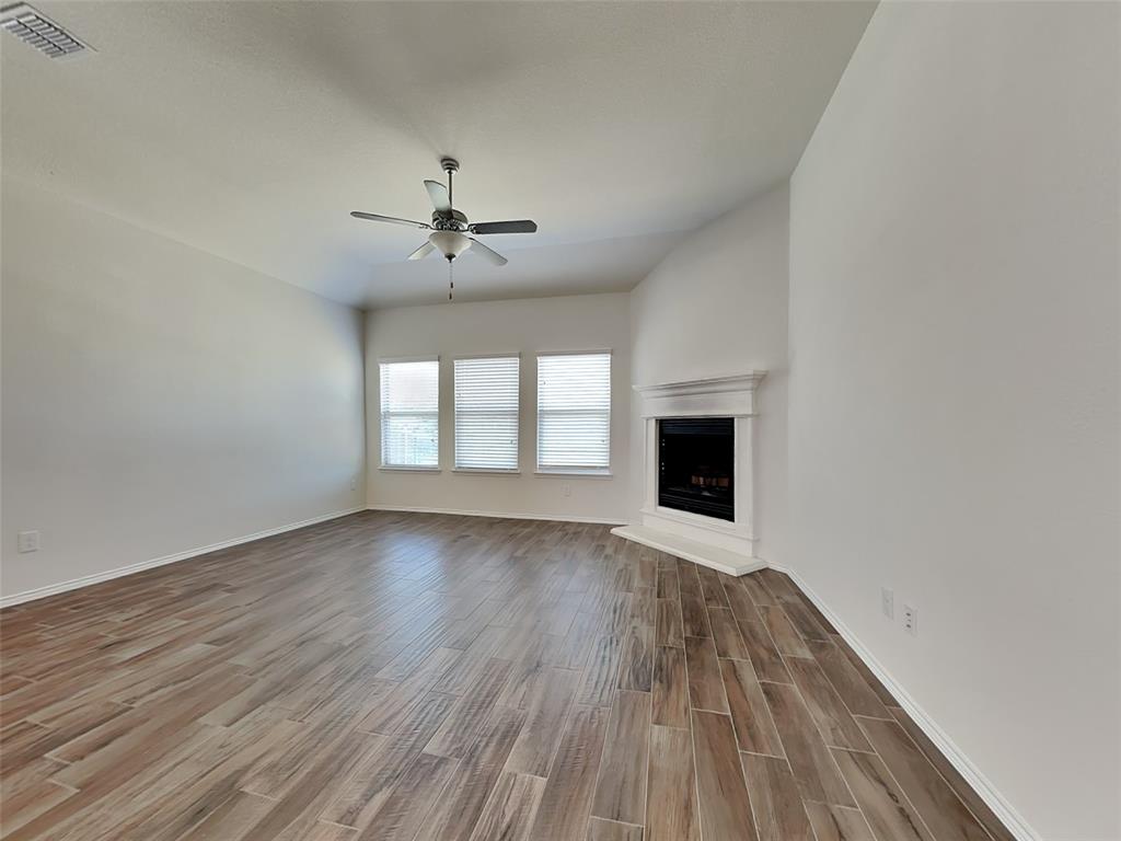 506 Robinson Way Fate, TX 75189 - Photo 4 of 30 Unfurnished living room featuring wood tiled floors, a fireplace with raised hearth, and a ceiling fan