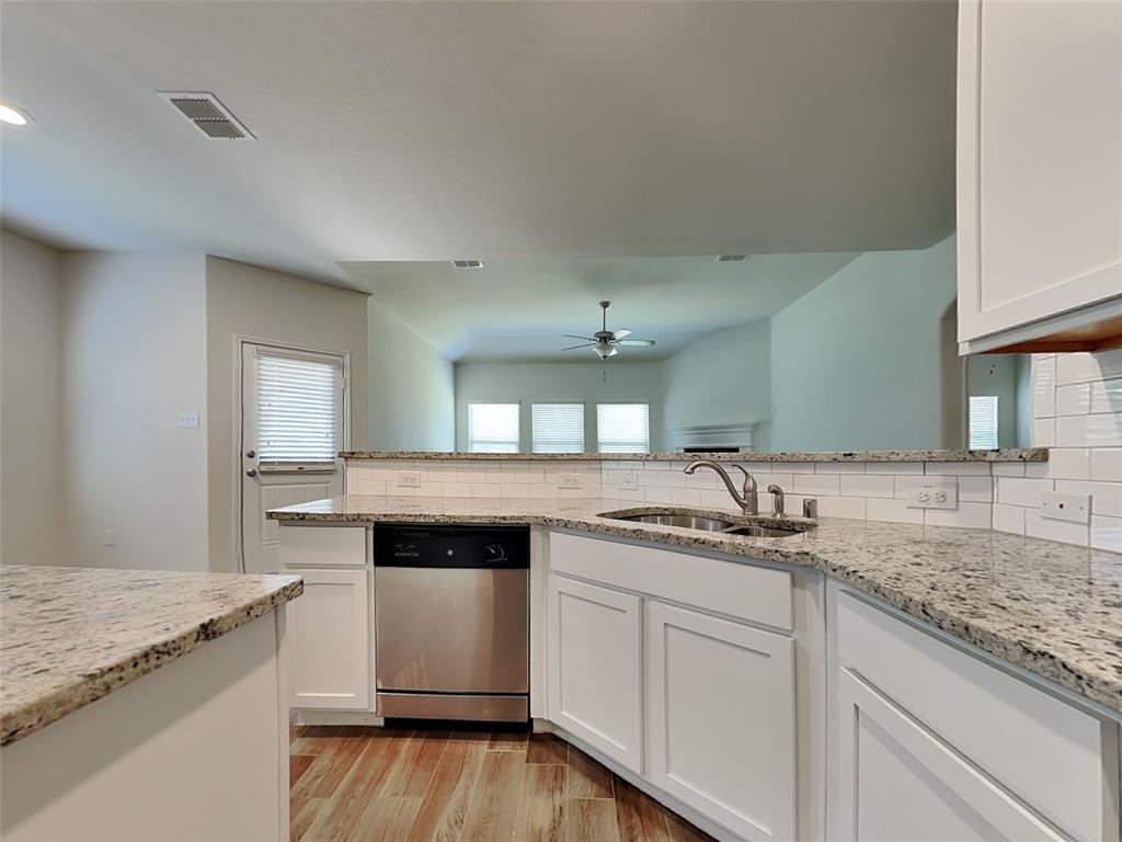 506 Robinson Way Fate, TX 75189 - Photo 5 of 30 Kitchen with light wood-type flooring, light stone countertops, stainless steel dishwasher, white cabinets, and decorative backsplash