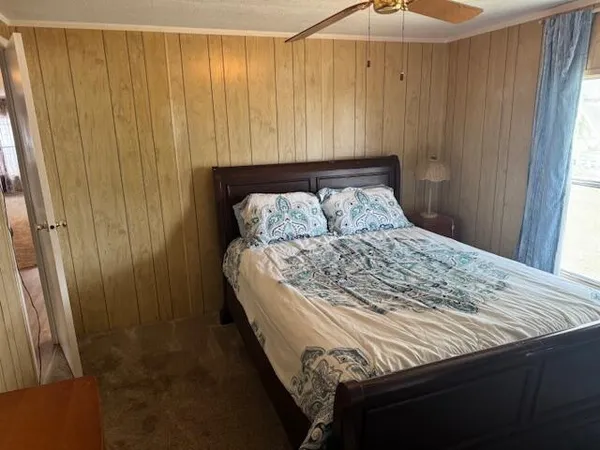 a bed sitting in a bedroom next to a window and a curtain