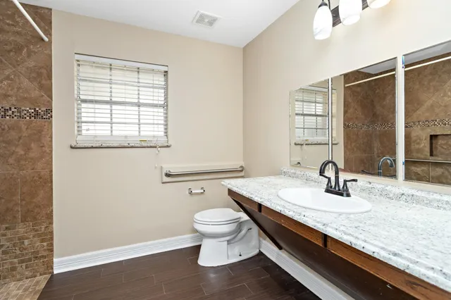 a bathroom with a granite countertop sink a toilet and a mirror