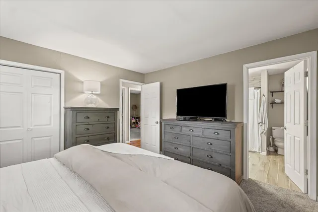 a bedroom with a bed and a flat screen tv in white dresser
