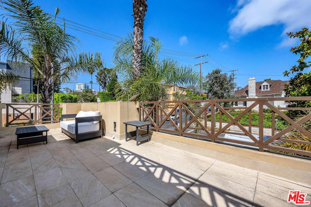 10555 Ashton Avenue, Unit 201 Los Angeles, CA 90024 - Photo 12 of 33 a view of a patio with a table and chairs under an umbrella with palm trees