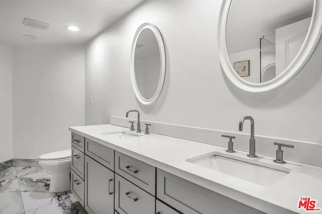 a bathroom with a granite countertop toilet a sink and a mirror