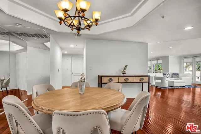 a dining room with wooden floor a chandelier a glass table and chairs