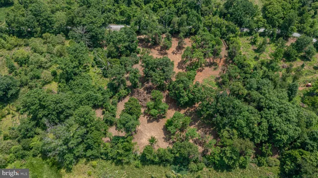 an aerial view of residential house with outdoor space and trees all around