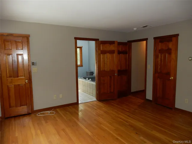 a view of an empty room with wooden floor and closet