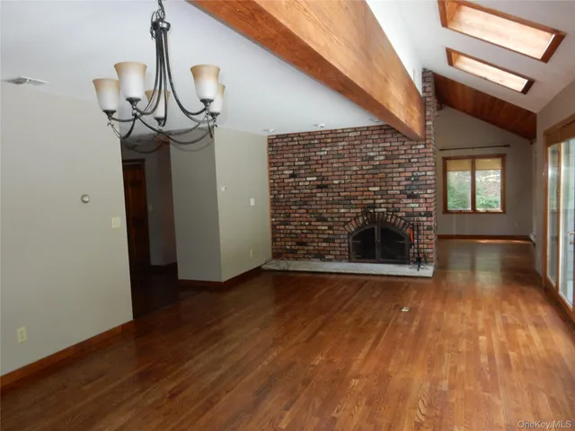 a view of a livingroom with wooden floor a fireplace and a window
