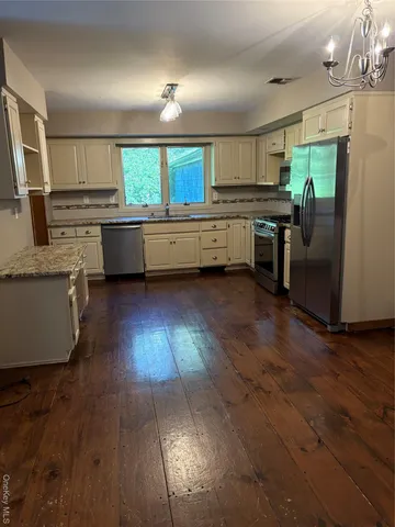 a kitchen with stainless steel appliances granite countertop a sink cabinets and wooden floor