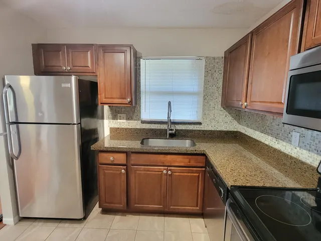 a kitchen with granite countertop a sink stove and refrigerator