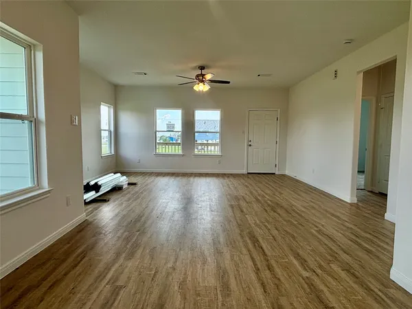 a view of an empty room with window and wooden floor