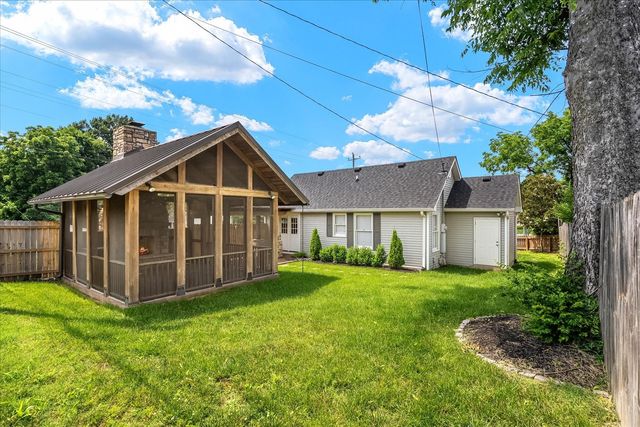 a view of a house with a yard and large trees