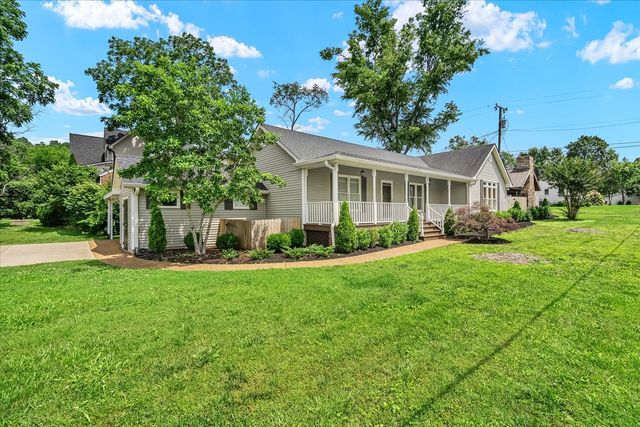 a front view of a house with a garden and trees