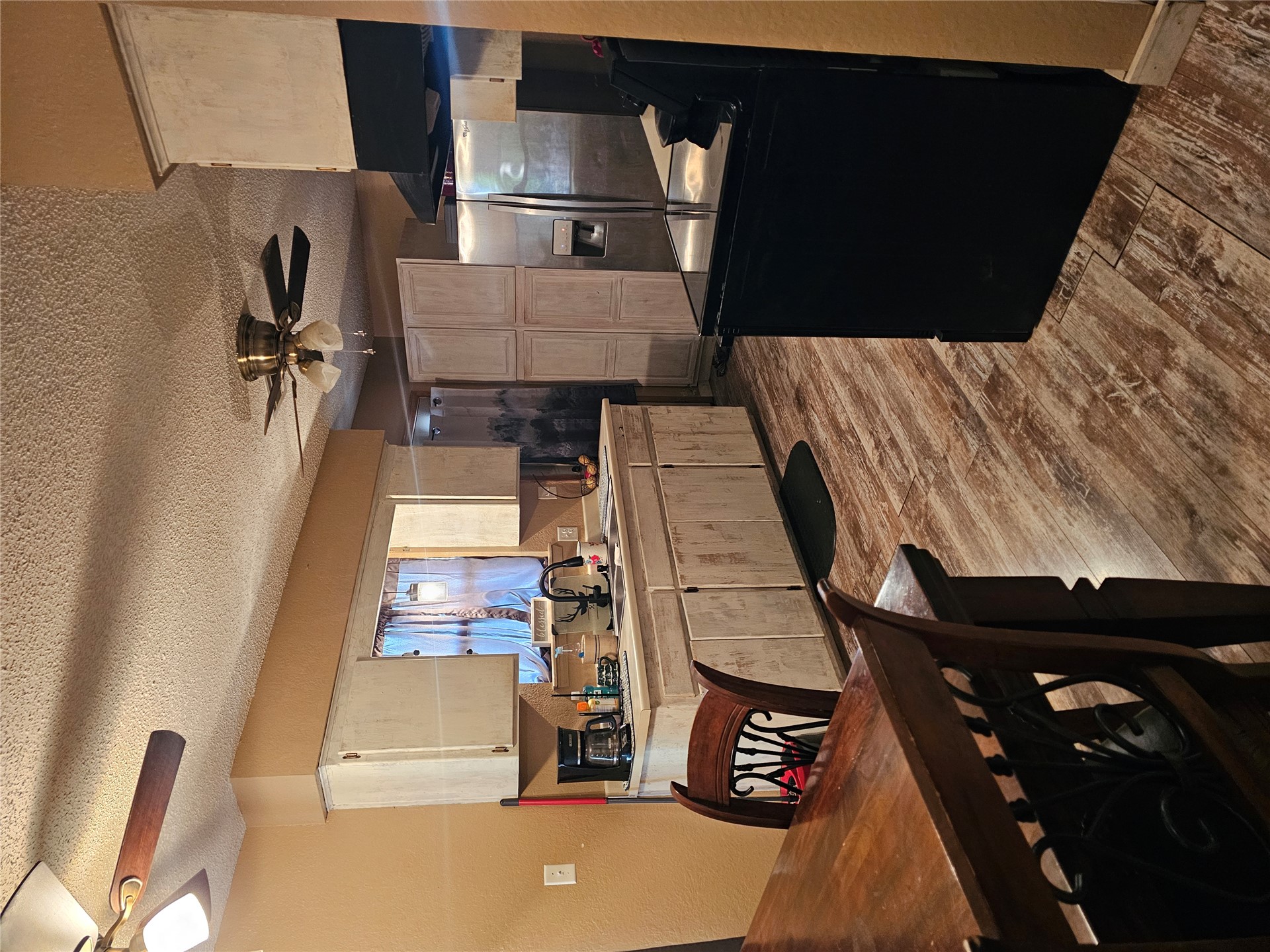 106441 South 4163rd Road Checotah, OK 74426 - Photo 17 of 17 Kitchen featuring wood-finish flooring, two ceiling fans, white cabinetry, a stainless steel refrigerator, and a black range