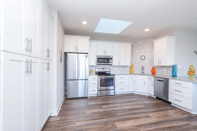 a kitchen with white cabinets white stainless steel appliances and wooden floors