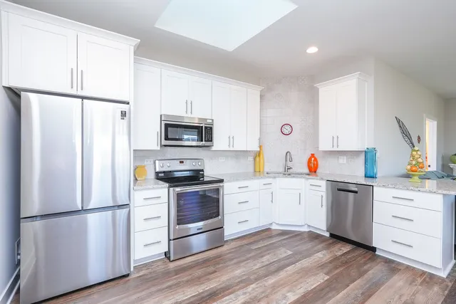 a kitchen with granite countertop a refrigerator oven a sink dishwasher and a stove with wooden floor