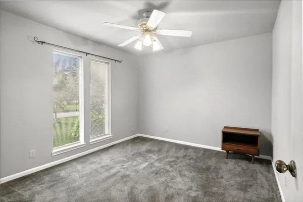 an empty room with a chandelier fan and closet