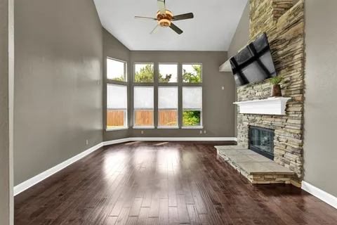 wooden floor in an empty room with a fireplace and a window