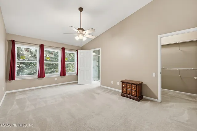 an empty room with windows and ceiling fan