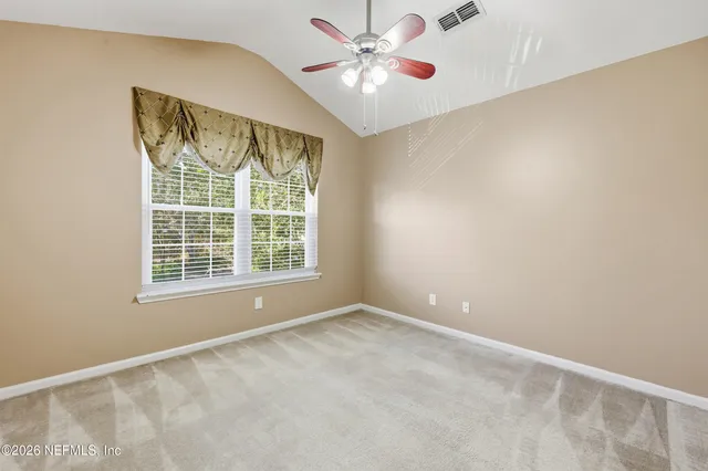 an empty room with a chandelier fan and windows