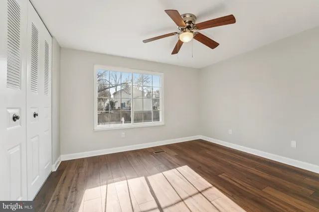 an empty room with wooden floor fan and windows