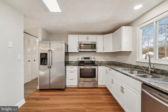 a kitchen with granite countertop a refrigerator stove and sink