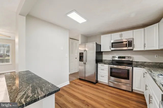 a kitchen with granite countertop a stove top oven a sink and a microwave