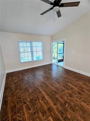 a view of an empty room with a window and wooden floor
