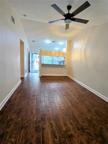 a view of a room with wooden floor fan and windows