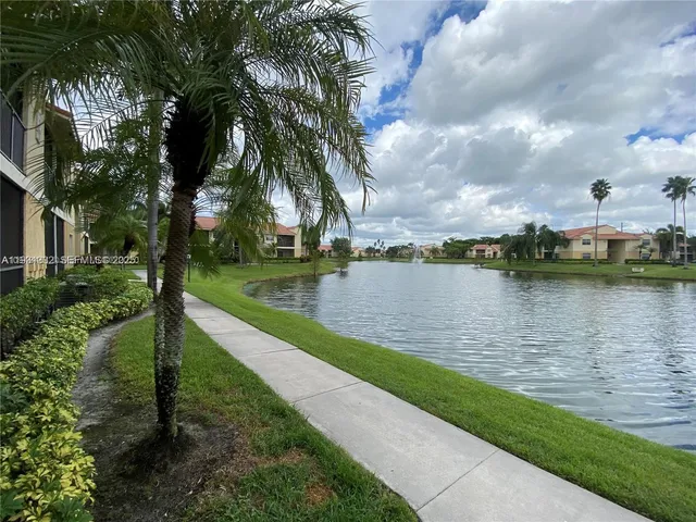 a view of a lake with a big yard and a large tree