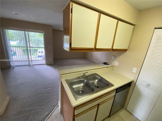 a view of an empty room with a sink and wooden floor
