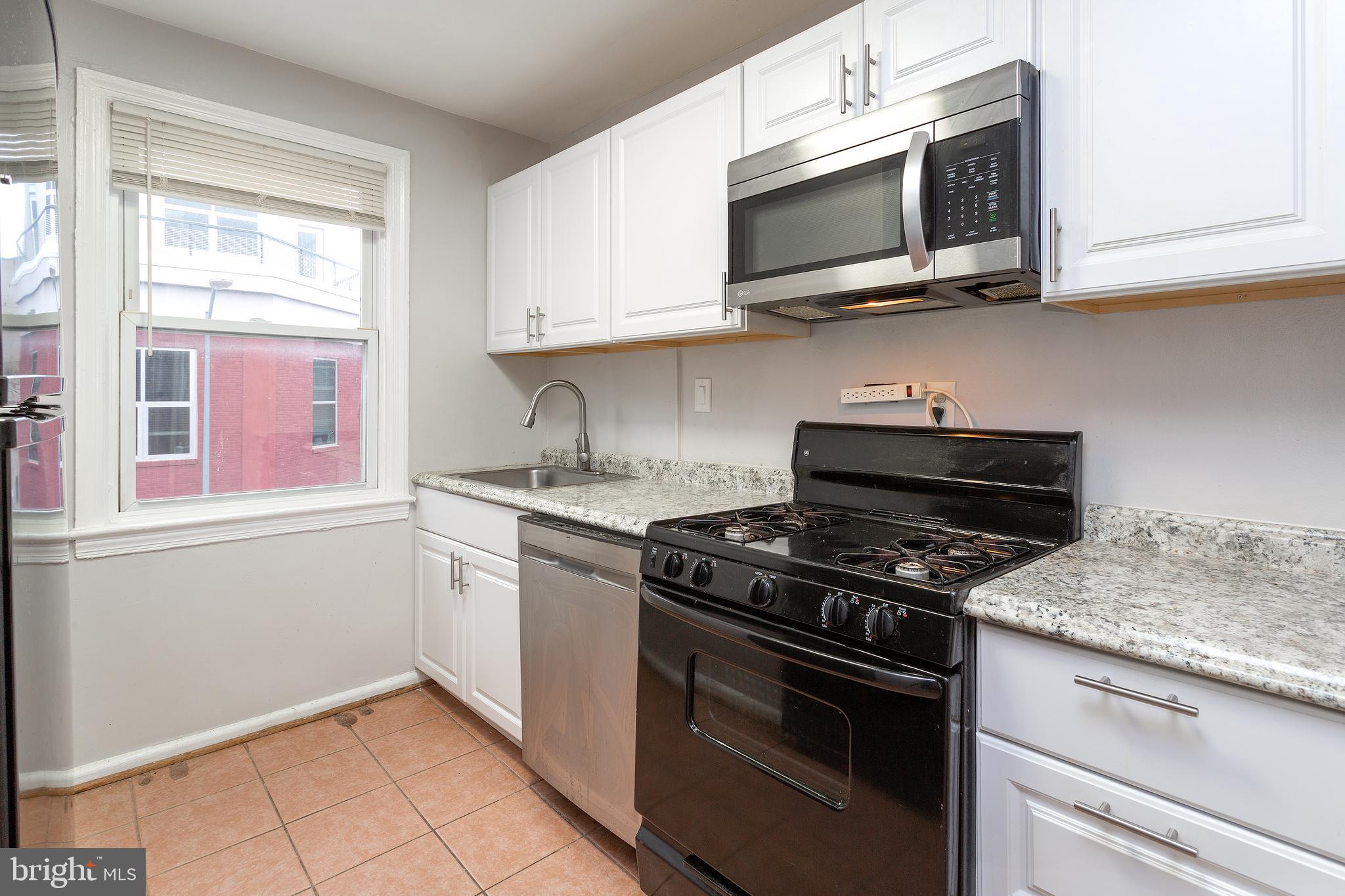 2415 Ontario Road Northwest, Unit 301 Washington, DC 20009 - Photo 8 of 25 a kitchen with stainless steel appliances granite countertop white cabinets and a stove top oven