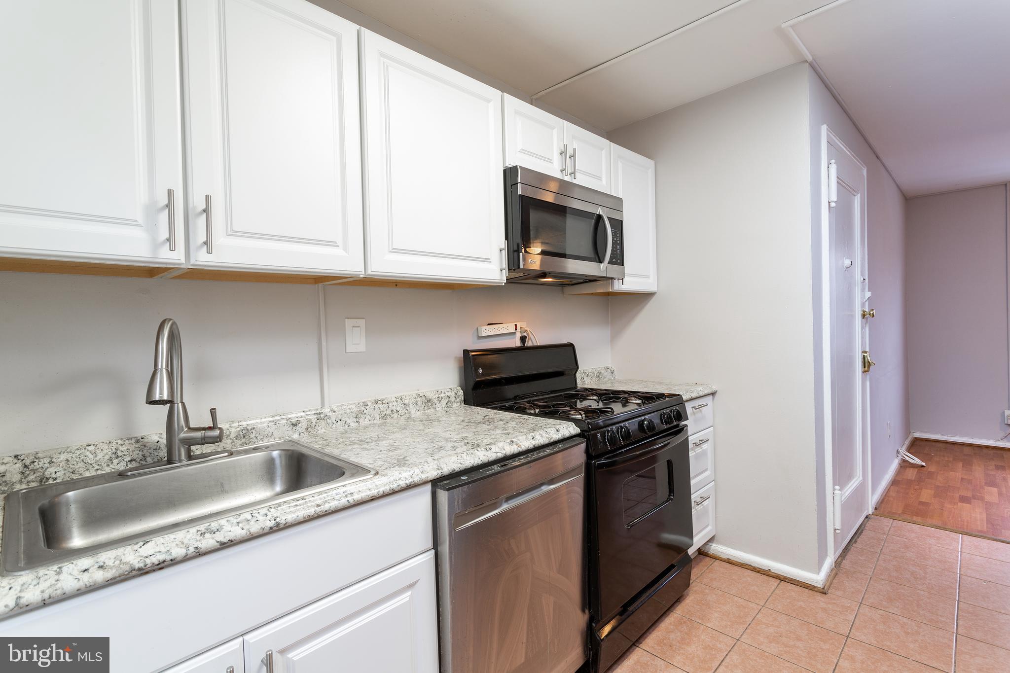 2415 Ontario Road Northwest, Unit 301 Washington, DC 20009 - Photo 9 of 25 a kitchen with stainless steel appliances granite countertop a sink a stove and microwave