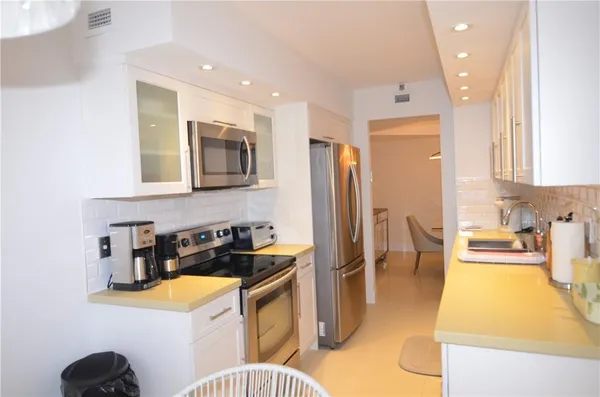 a kitchen with stainless steel appliances granite countertop a sink a stove a refrigerator a washer and dryer