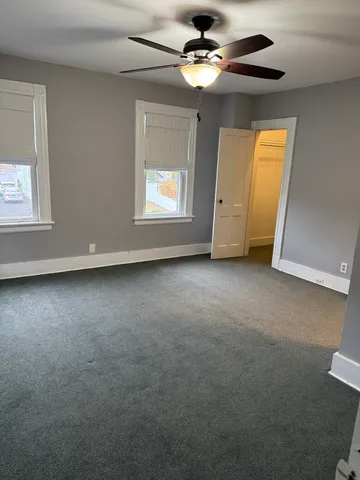 an empty room with windows and fan