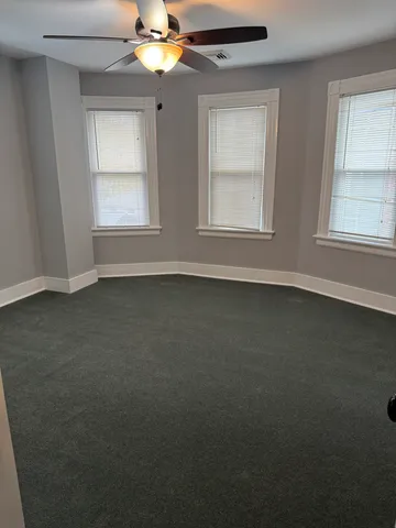 an empty room with windows and chandelier fan