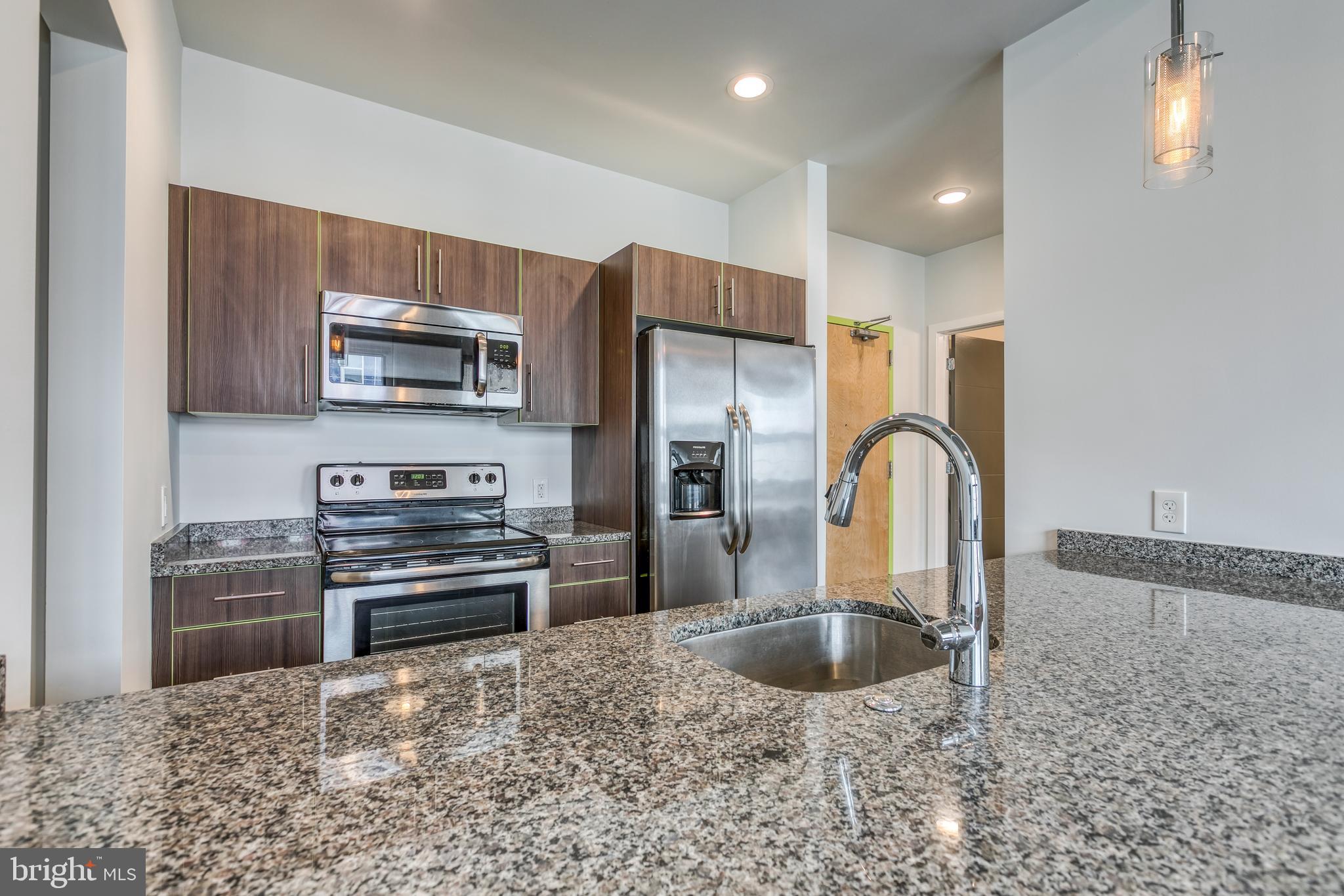 4800 Brown Street, Unit 306 Philadelphia, PA 19139 - Photo 3 of 22 a kitchen with kitchen island a sink stainless steel appliances and a counter top