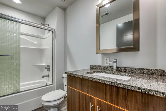 a bathroom with a granite countertop sink toilet and shower