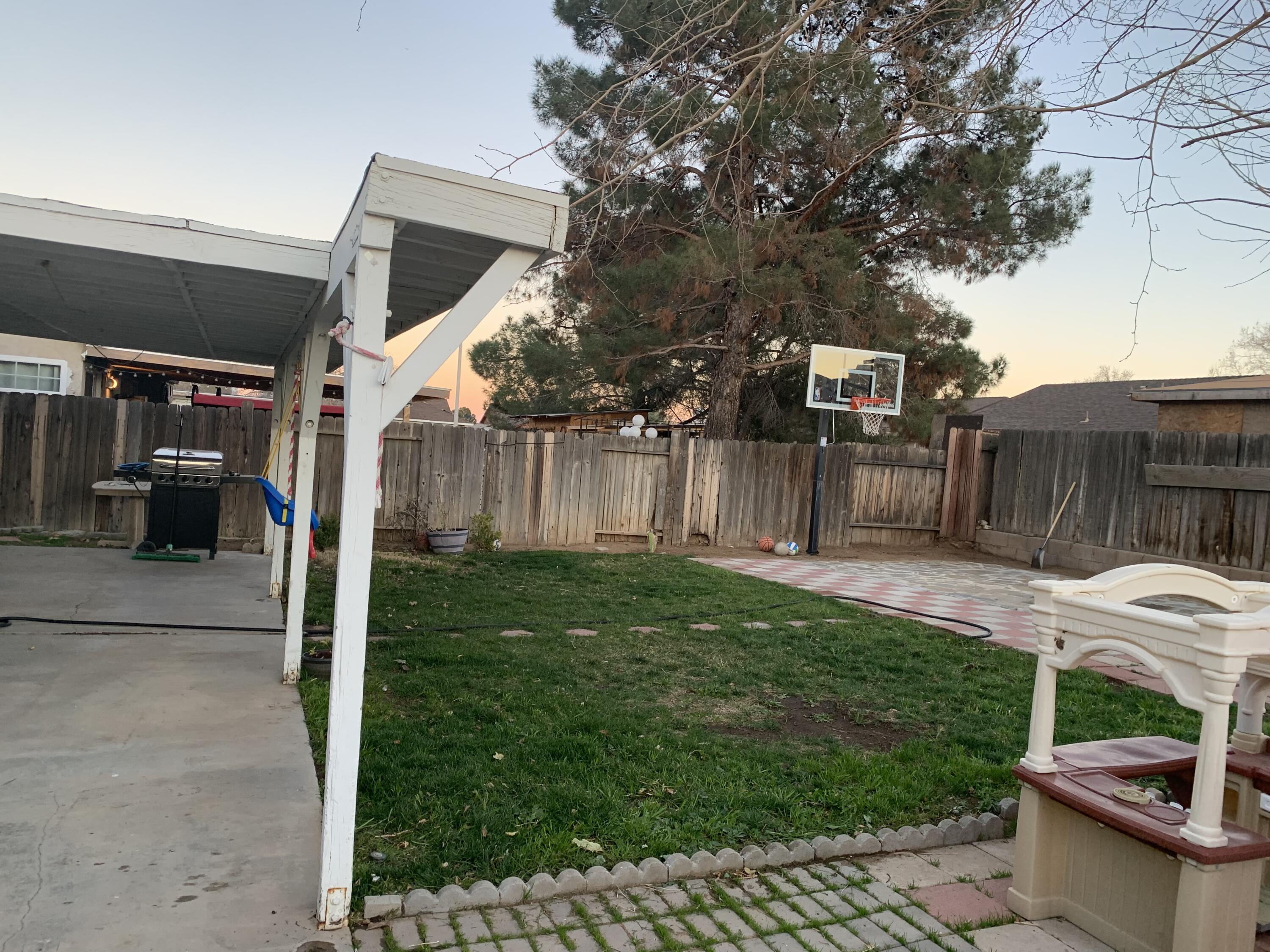 3096 East Avenue R-5 Palmdale, CA 93550 - Photo 21 of 22 a view of a backyard with table and chairs potted plants and a large tree